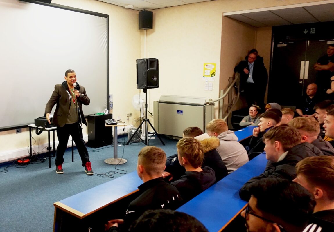 A rapper called Testament performs hip hop and beatboxing to a lecture theatre of construction students.