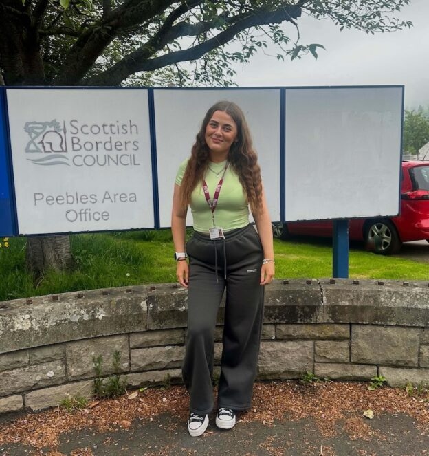 Neve Hay standing next to a Scottish Borders Council sign in an outdoor setting