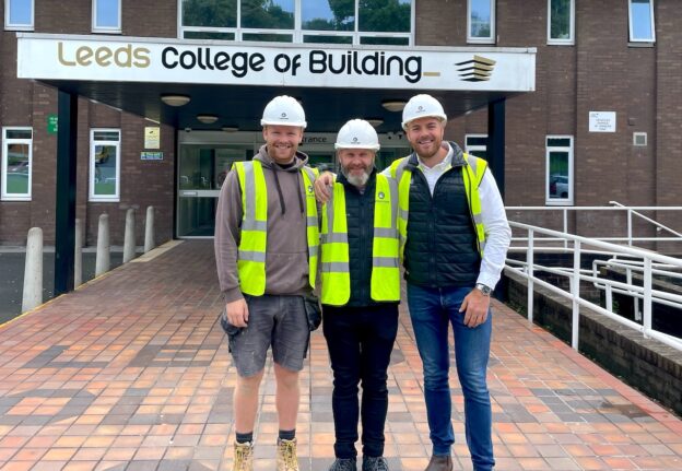 Former student and quantity surveyor John Brightmore stands between Leeds College of Building joinery apprentice Will King on his left and former apprentice and project manager Josh Turner on his right. The group stand outside the main Leeds College of Building entrance to the North Street Campus.