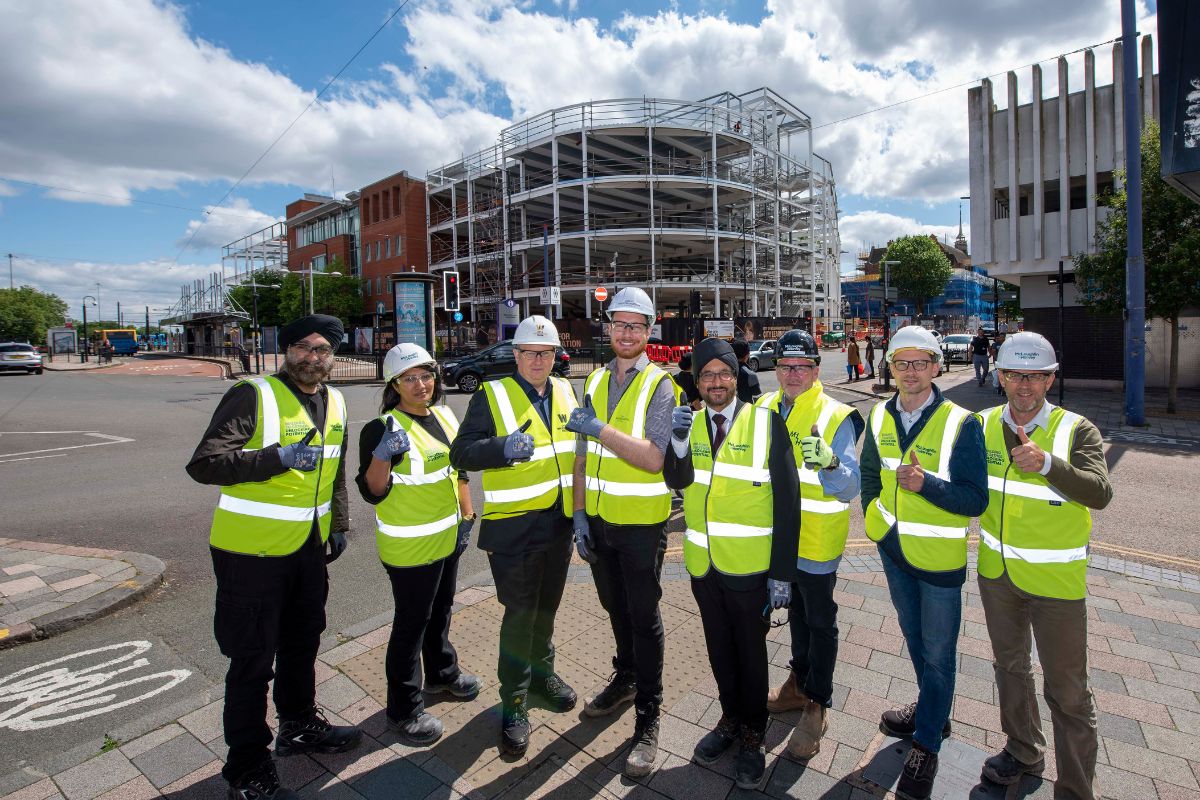 City partners in high-vis jackers standing in front of the completed steelwork of the new City of Wolverhampton College campus