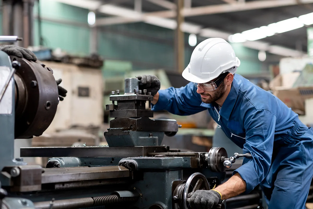 Industrial engineer worker in white hard hat working with production machinery in the factory