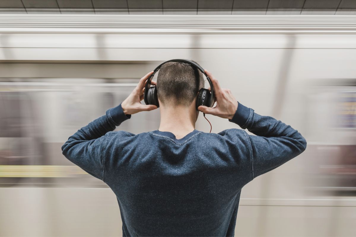 young man with headphone on waiting on a train platform, pexels stock