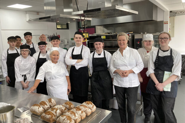 Group of students in whites and aprons in training kitchen with Rachel Allen (third from right)