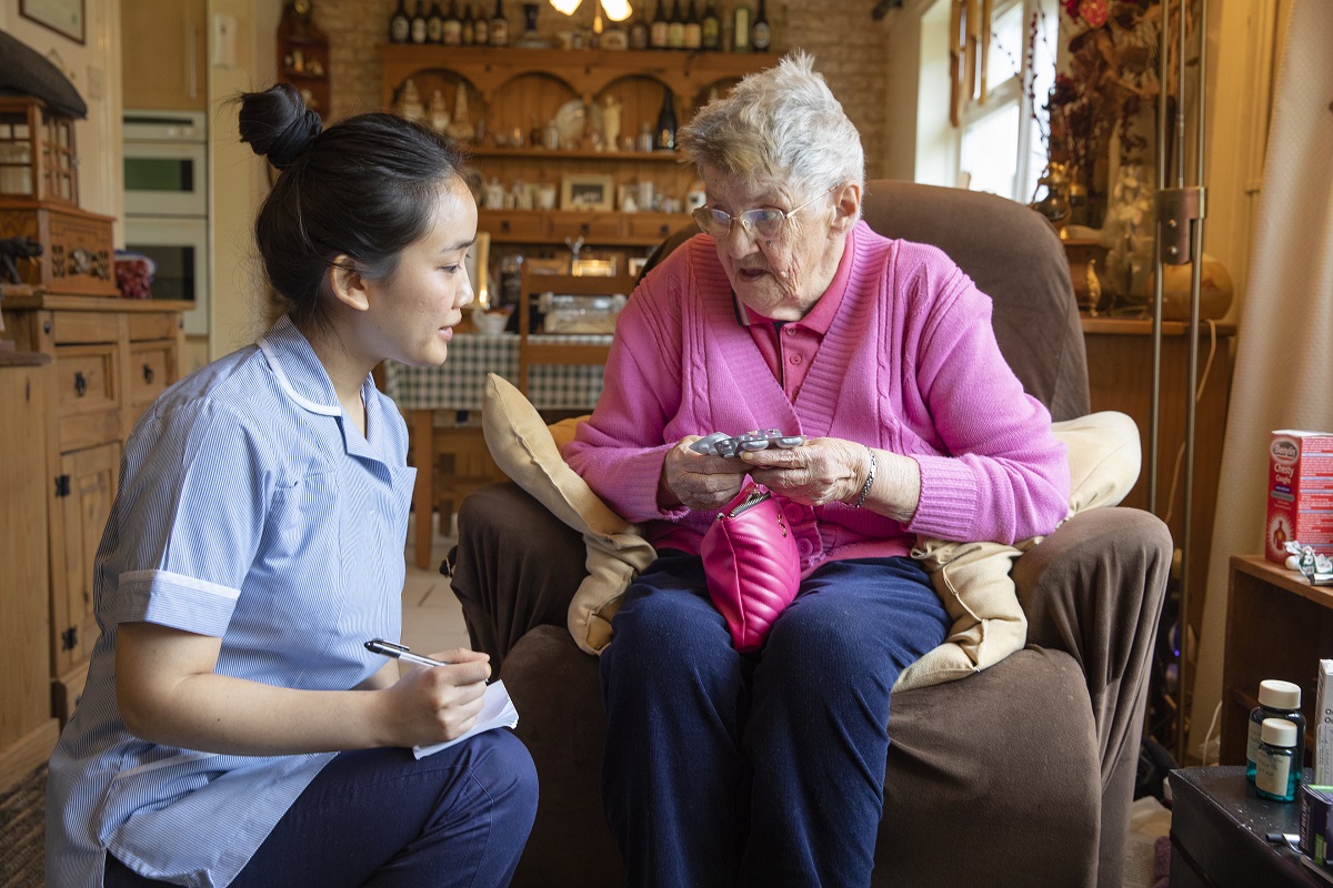 Care worker kneeling next to elderly patient