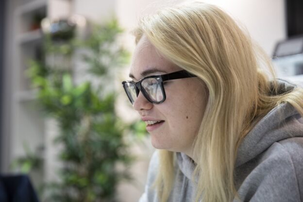 Female learner wearing glasses leaning forward towards a computer screen