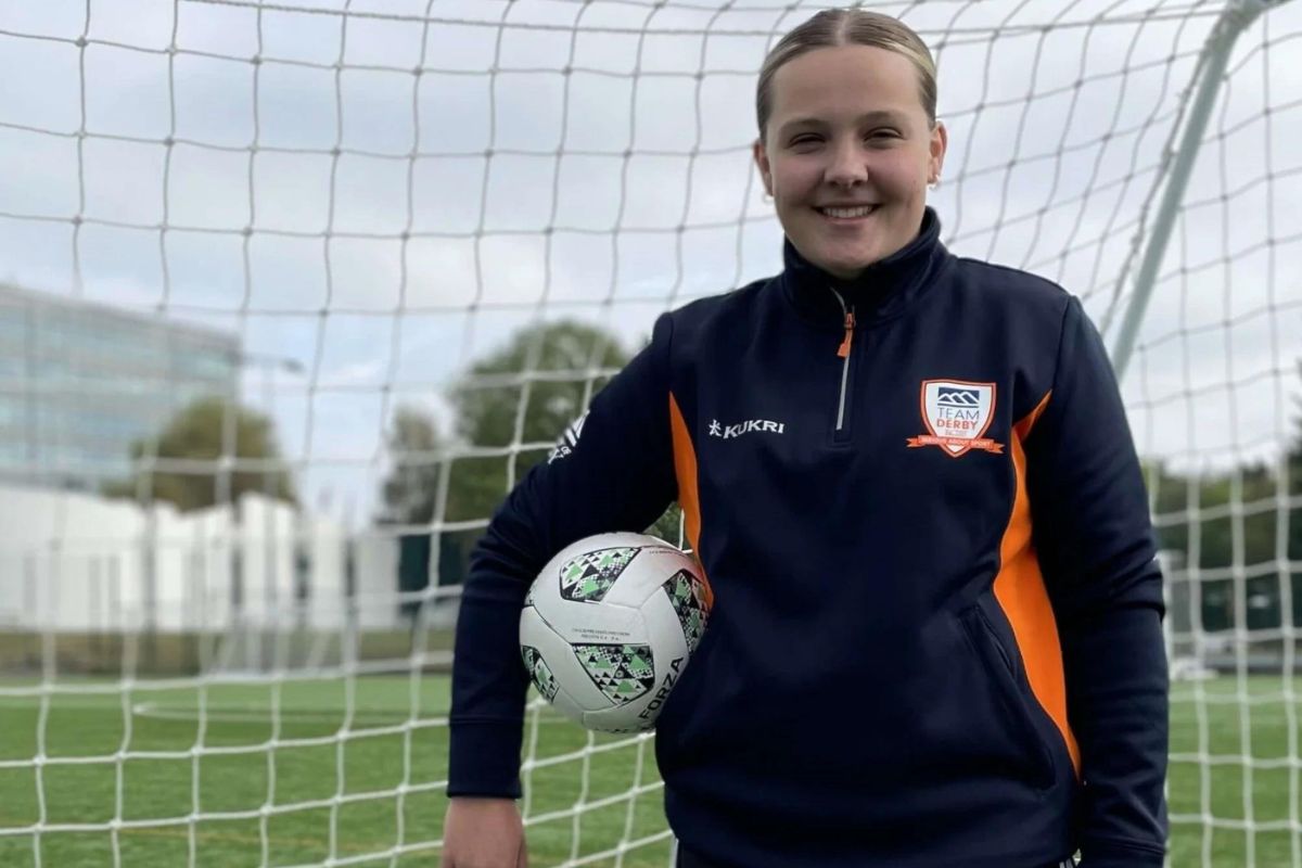 A young female footballer is pictured holding a ball.