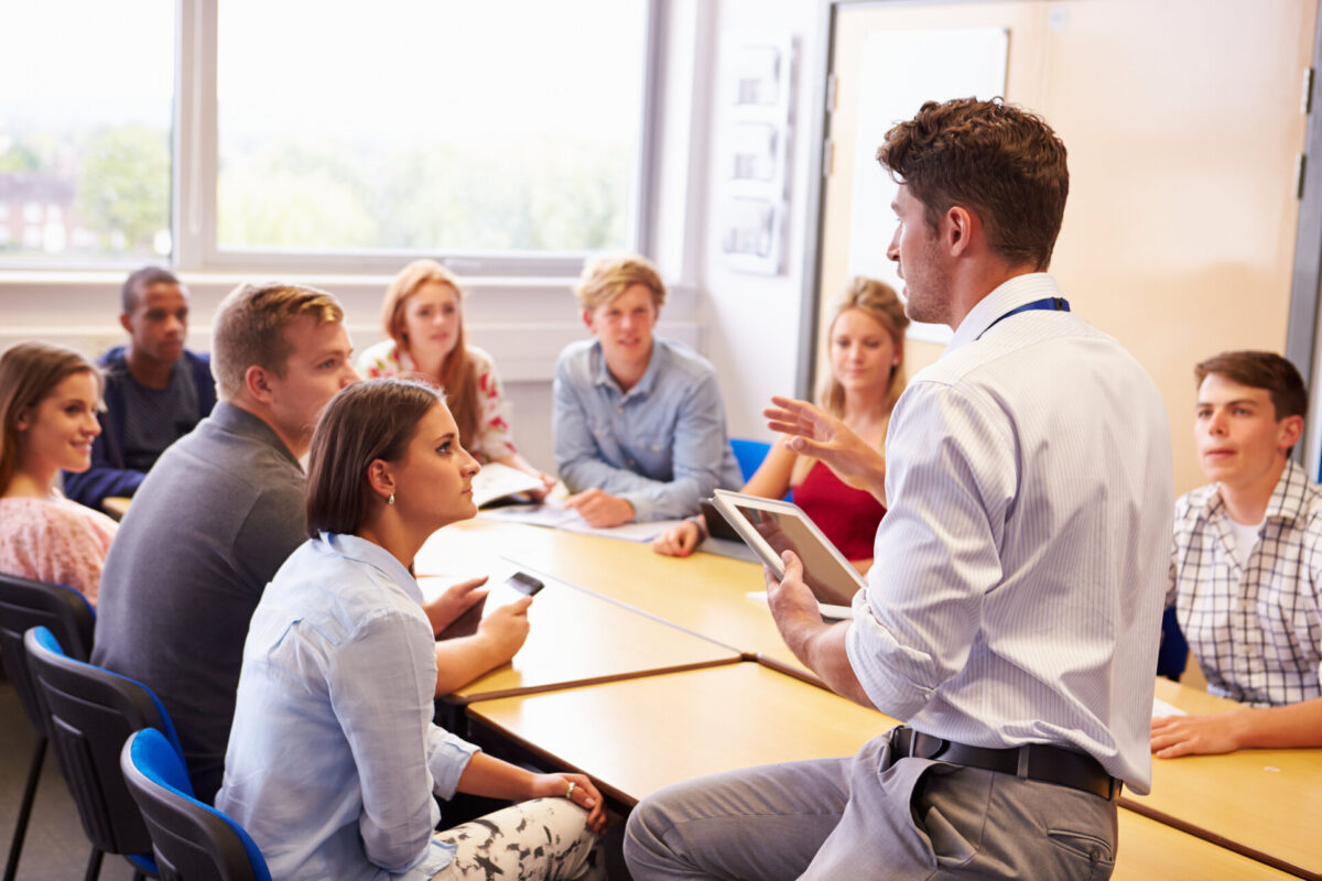 Teacher With College Students Giving Lesson In Classroom