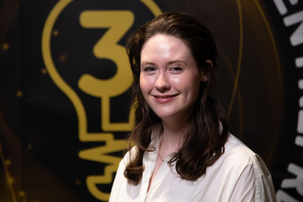 A woman in a white shirt with dark hair smiling.