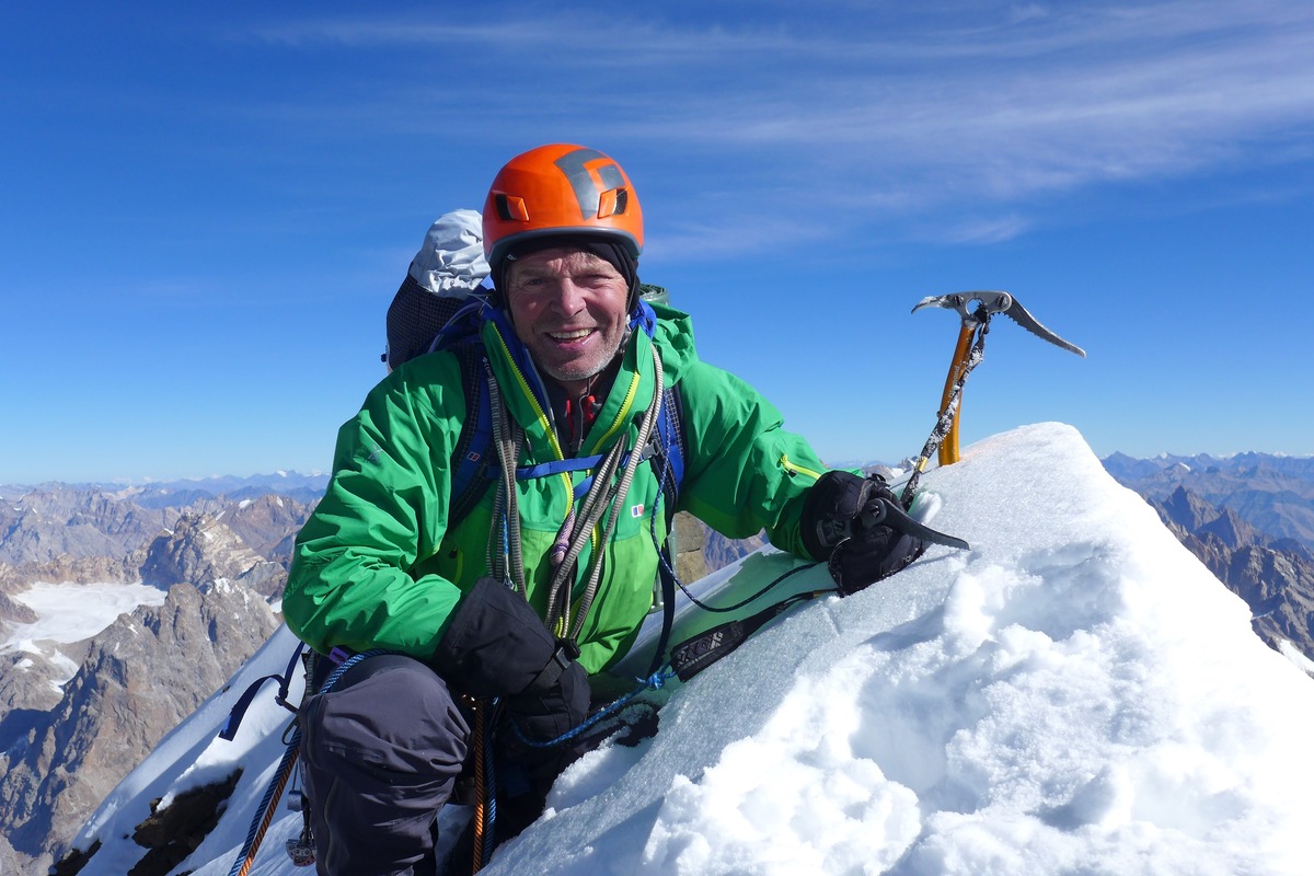 A smiling man is pictured climbing a snowy mountain