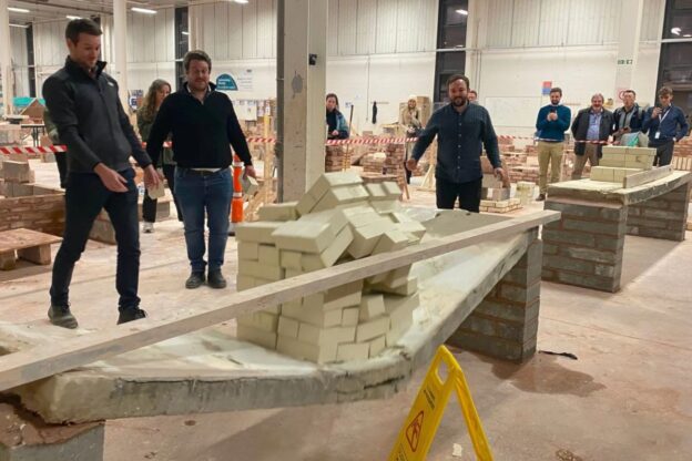 Three male engineers watch as large concrete slabs collapse in a demonstration held at the Leeds College of Building workshop.