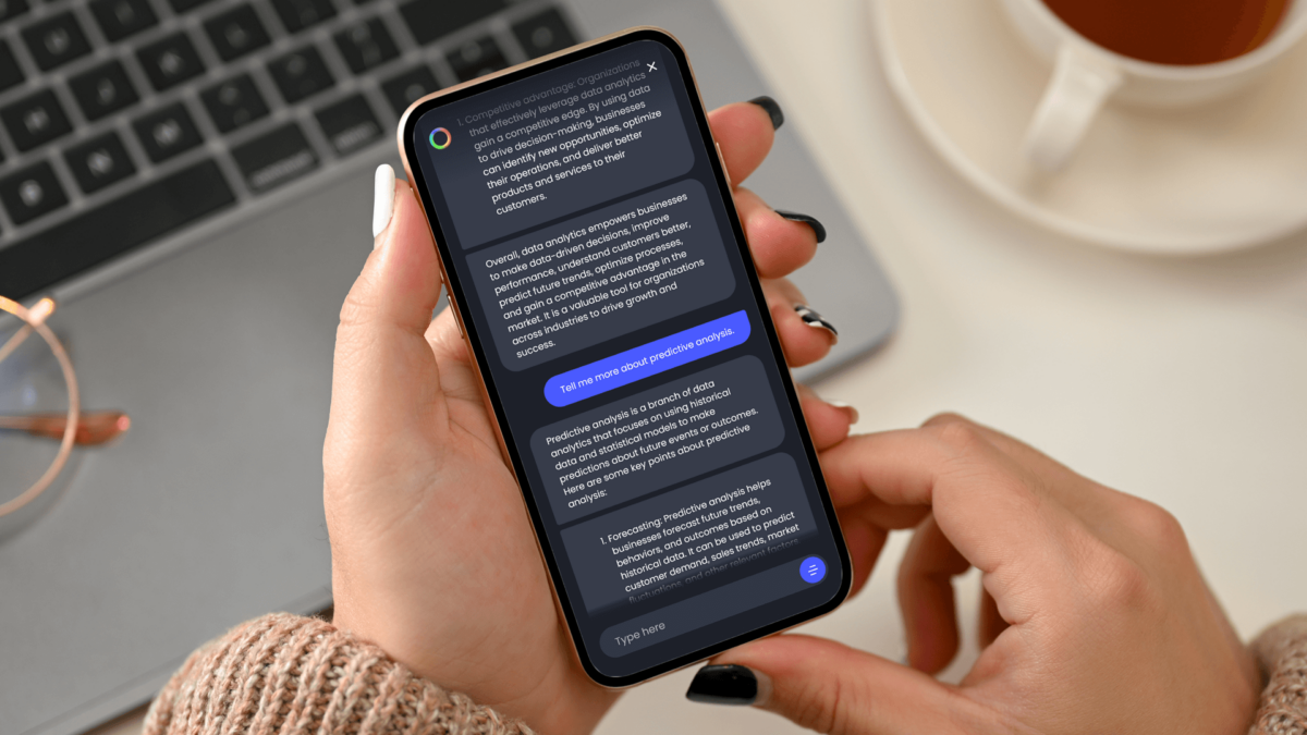 Image of a woman's hands holding an iPhone. On the screen there is a chat with an AI-powered learning assistant provided by LIBF. There is a laptop keyboard in the background of the photo.