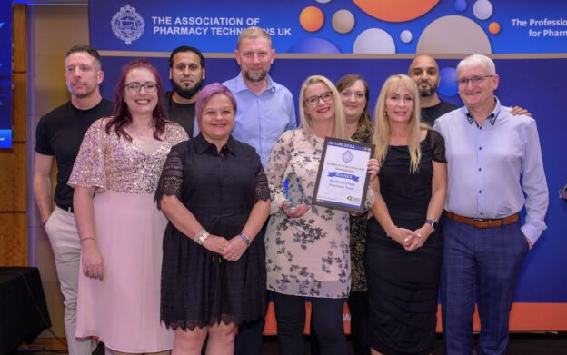 The Bradford College pharmacy team pose together onstage with their trophy at the APTUK awards.