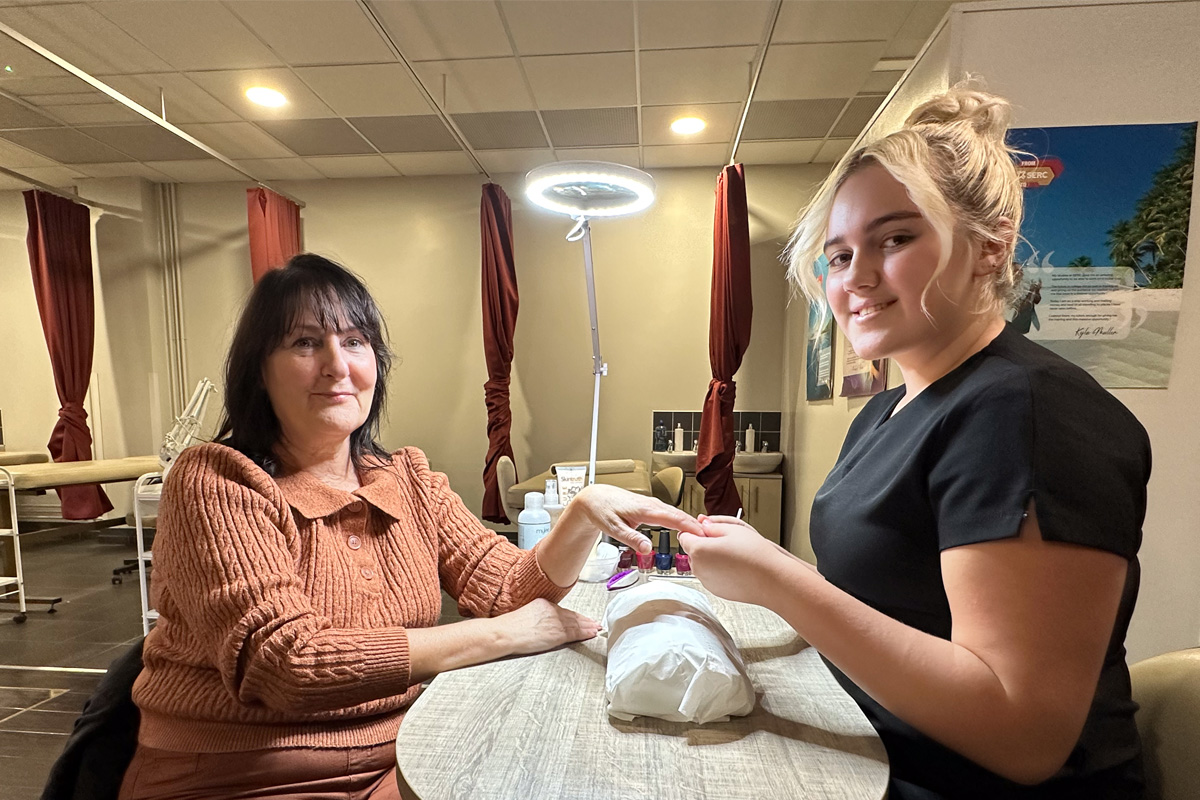 Beauty therapy student giving another female a hand treatment.