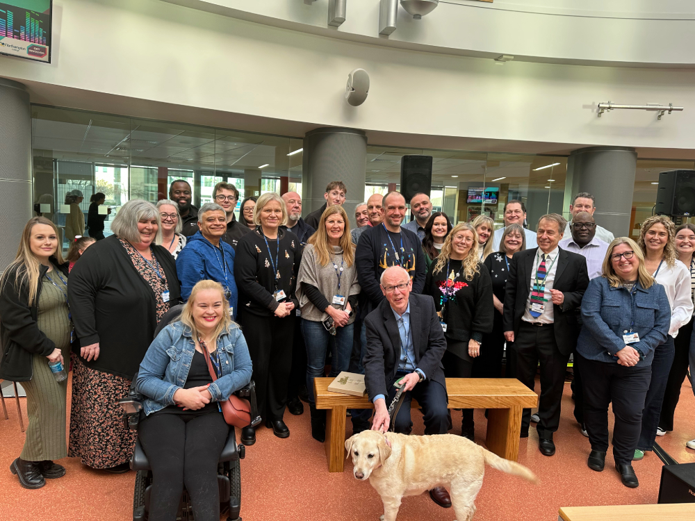 Patrick Leavey sits on his new bench surrounded by colleagues from Northampton College