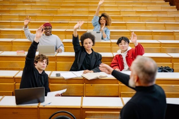 students in a lecture theatre with their hands raised