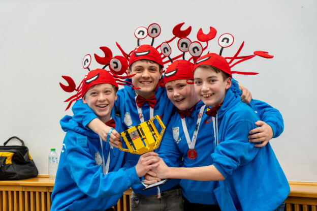 The winning four students holding a trophy made from LEGO