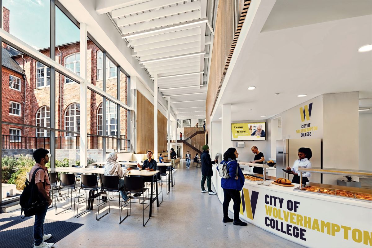 Cgi of the entrance foyer at the new CLQ campus with a curved reception desk with the college logo on and a glass atrium area with tables and chairs